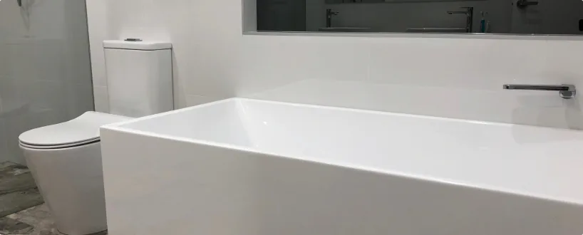 A new bathroom renovation featuring a free-standing bathtub next to a modern toilet, with sleek tile work